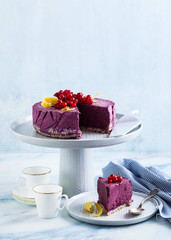 classic blueberry lemon cheesecake on a cake stand on a marble table.