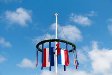 Festive wreath with little flag in front of blue sky