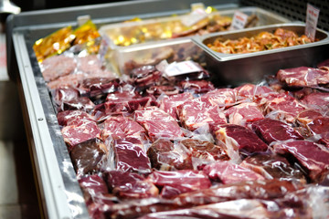 Beef, veal, lamb fresh raw steaks are packaged in vacuum and sold on counter of store.