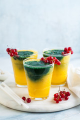 two colored fresh smoothies in glasses with fresh berries. orange banana juice with spirulina powder. detox breakfast. healthy eating