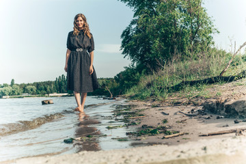 young woman walks by the river bank