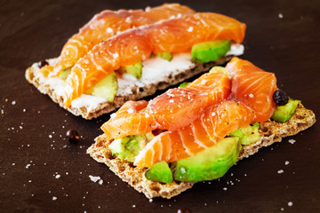 Two Crisp sandwiches with avocado and salmon. Slate background. Selective focus. Toned photo.