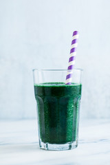 a tall glass of green fruit smoothie with Hawaiian spirulina on a marble table. healthy full breakfast