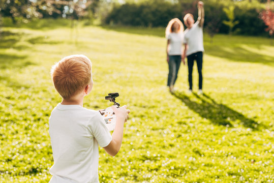 boy playing with drone while parents standing behind at park - Powered by Adobe