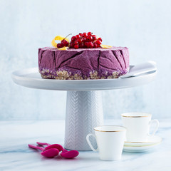 frozen blueberry lemon cake from ice cream and fresh berries on a cake stand on a marble table. summer festive dessert