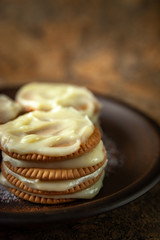 Cookies smeared with custard cream on a dark plate against a dark background