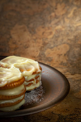 Cookies smeared with custard cream on a dark plate against a dark background