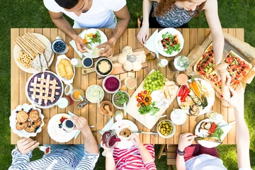 Fotobehang Top view on wooden table with pastry, pizza and fruits during garden party © Photographee.eu