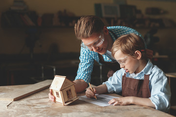 Father and son with a wooden house