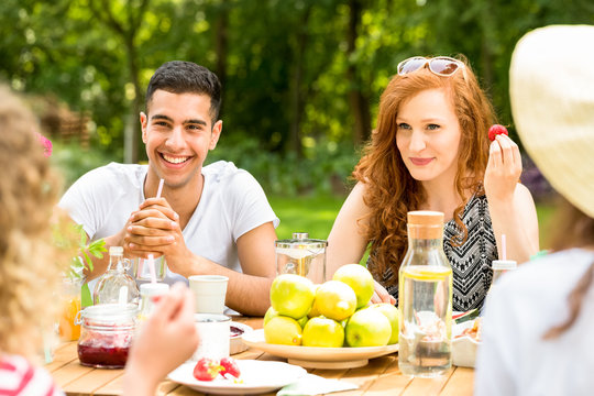 Smiling red-haired woman and spanish man enjoying outdoor party