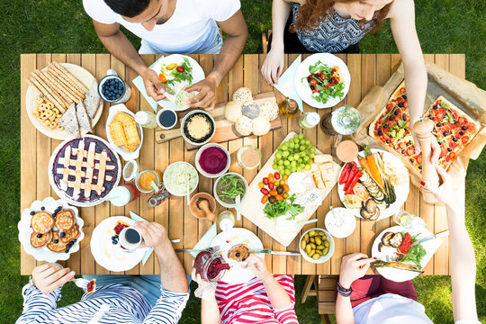 Top view on wooden table with pastry, pizza and fruits during garden party