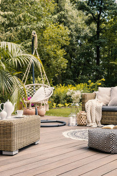 Real photo of a hanging chair and rattan furniture on a wooden terrace of a summer house