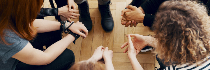 High angle view of hands of people in group therapy, talking and supporting each other - obrazy, fototapety, plakaty
