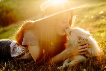 Girl holding a dog breed of the Dwarf (Pomeranian) Spitz. Dog kissing girl. Background toning for instagram filter. Sunset light