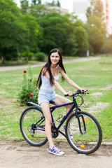 Plakat Teen girl with bicycle in a park.