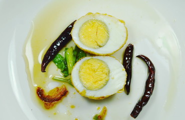 fried egg half cut dressing sweet tamarind sauce topping chili on plate