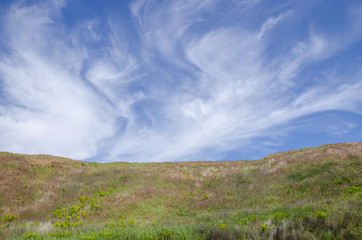 the top of a hill under the sky with clouds