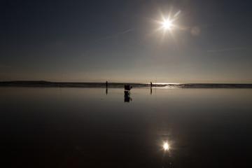 Two fisherman standing on the shore line to the ocean and fishing with their rods