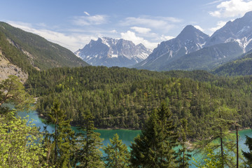 View over a little lake with turquoise water and mountains with snow in background