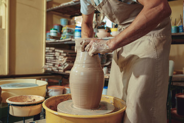 Creating a jar or vase of white clay close-up. Master crock. Man hands making clay jug macro.