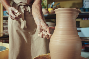 Creating a jar or vase of white clay close-up. Master crock. Man hands making clay jug macro.