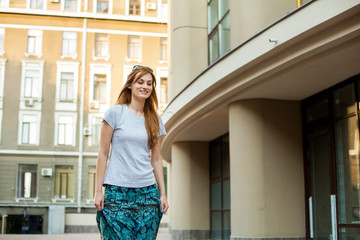 happy redhead hipster teenager in a gray shirt and long blue skirt walking in the street. Concept of modern freedom hipster human