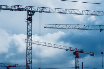 Many cranes on building site - construction cranes on blue sky