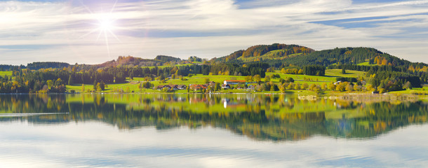 Panorama Landschaft in Bayern mit Alpen im Allgäu und Spiegelung im Forggensee