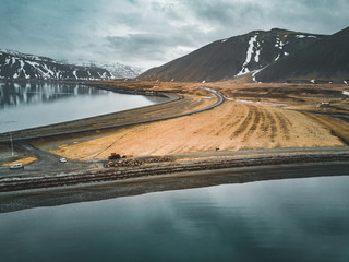 Aerial view of road 1 in iceland with bridge over the sea in Snaefellsnes peninsula with clouds, water and mountain in background