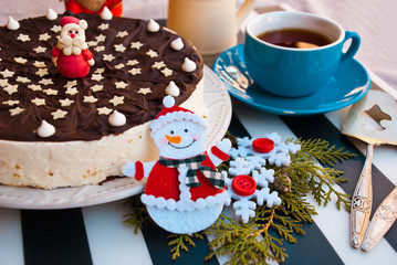 Christmas card with chocolate cake decorated with santa figure, and snowman ahead. Xmas food background.