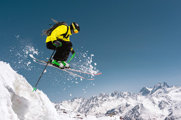 A skier in full sports equipment jumps into the precipice from the top of the glacier against the...