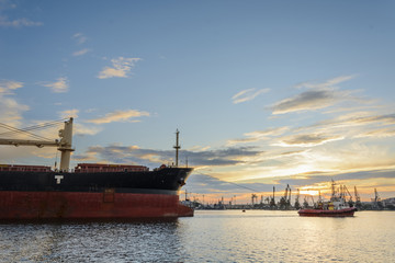Tug boat entering the harbor with big cargo boat.