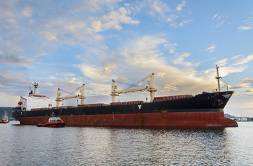 Tug boat entering the harbor with big cargo boat.