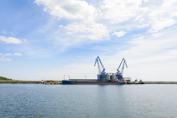Fototapeta na wymiar Crane and cargo ship in the Balchik bay in Bulgaria.