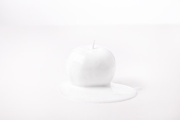 Apple covered in a white dripping substance, shot against a white background. 