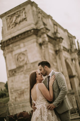 Fototapeta na wymiar Young wedding couple by Arch of Constantine in Rome