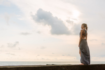 Pretty woman in summer dress on pier look forward to the future and happy smile. Sexy lady on sea beach sunset or ocean sunrise. Travel, explore, active yoga and meditation lifestyle concept.