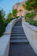 Narrow staircase with handrails going upwards to a high wall with an ornament with a jagged top.