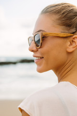 Fototapeta na wymiar Close up portrait of pretty woman in casual summer dress and wooden sunglasses. Sexy lady on sea tropic beach sunset or ocean sunrise. Travel, explore, active yoga and meditation lifestyle concept.