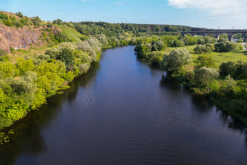 Fototapeta na wymiar River with green shores against the bridge