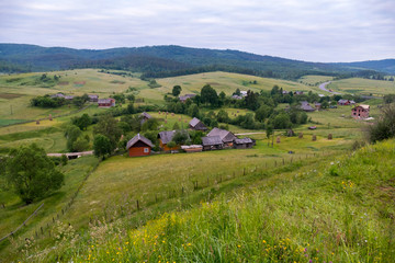 Small rural houses with courtyards on the background of wide green mountain ranges