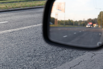 Side view mirror reflection of three-lane road in city