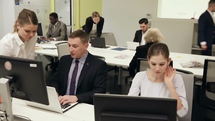 Successful coworkers engaged in business activities in busy open plan office