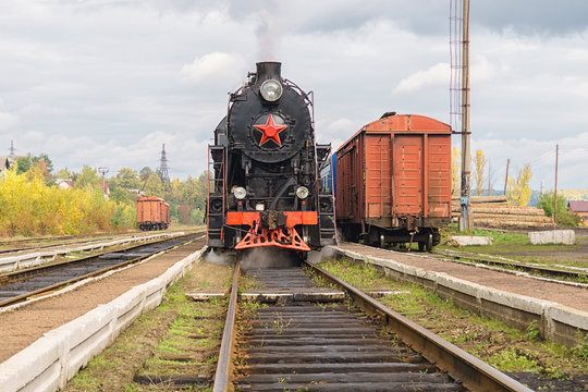 Vintage black steam locomotive train with wagons on station.
