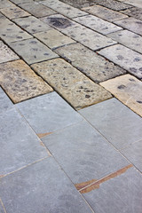 Restoratione of an old stone paving with new carved paving made with grey stone blocks in an italian pedestrian zone