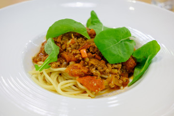 Spaghetti topped with ketchup, minced pork Put fresh tomatoes and sprinkle with rocket vegetables. Serve in a white plate.