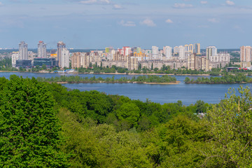 Fototapeta na wymiar Panorama of multi-storey buildings on the shore of the Dnipro River under the blue sky. Kiev. Ukraine