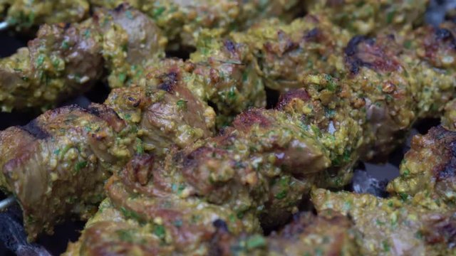 Camera moving across the top of marinated meat shish kabobs on a hot grill.