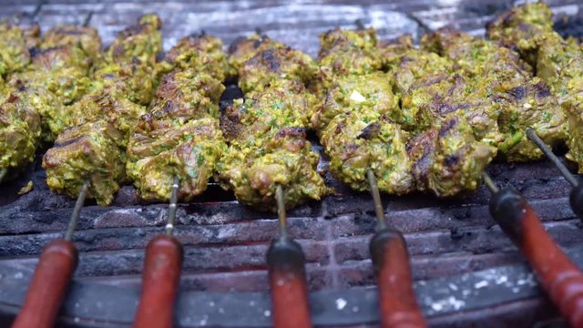 Closeup of shish kabobs on a hot grill with skewers.