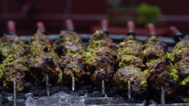 Extreme closeup of the end of marinated meath shish kabobs on a grill with skewers through them.